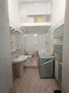 La salle de bains blanche est pourvue d'un lavabo et de toilettes. dans l'établissement Casa vacanze completa di tutto e anche di più, à Livourne