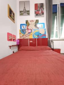 Un dormitorio con una cama roja con una pintura en la pared en Casa vacanze completa di tutto e anche di più, en Livorno