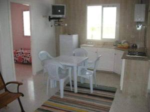uma cozinha com uma mesa branca e cadeiras brancas em Mahdia zone Touristique em Mahdia