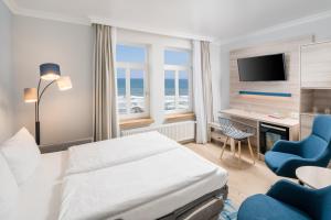 a hotel room with a bed and chairs and a television at Strandhotel Gerken in Wangerooge
