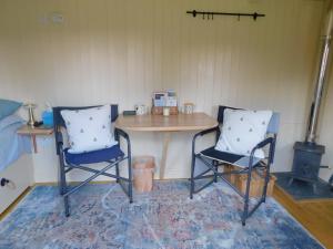 duas cadeiras e uma mesa num quarto com uma mesa em annes hatch hut 