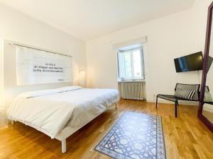 a white bedroom with a bed and a tv at La Casa del Poeta Enna - Pergusa in Enna