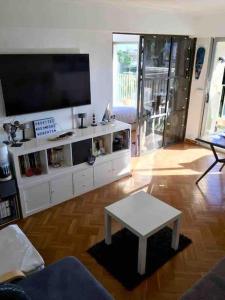 een woonkamer met een flatscreen-tv en een tafel bij Appartement climatisé avec piscines proche mer in Mandelieu-la-Napoule