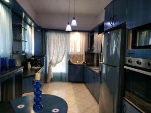 uma cozinha azul com uma mesa e um frigorífico em SandyKosta em Kiáton