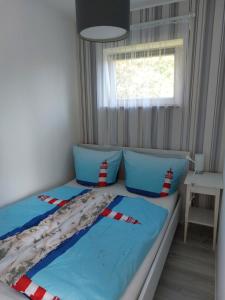 Schlafzimmer mit einem Bett mit blauer Bettwäsche und einem Fenster in der Unterkunft Ferienwohnung Eichhörnchen in Eckernförde