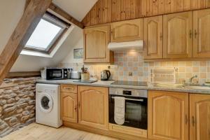 a kitchen with wooden cabinets and a washer and dryer at Duddings Country Cottages in Minehead