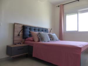 een slaapkamer met een bed met roze lakens en een raam bij EXCELLENT rapport Qualité Prix pour cet Appartement 3 étoiles Neuf 2P Tout Confort Résidence Golf Mesnana Tanger in Tanger