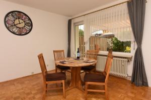 een eettafel met stoelen en een klok aan de muur bij Ferienhaus Bergverbunden in Fischen