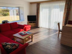 a living room with a red couch and a table at Apartmenthaus Florian in Lam