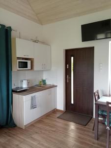 a kitchen with white cabinets and a brown door at Domki na Wzgórzu - Rospuda - Domek z sauną in Filipów