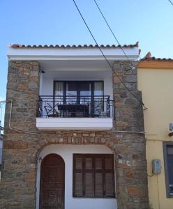 a villa with a balcony and a table on a building at Traditional Stone House in Moudhros