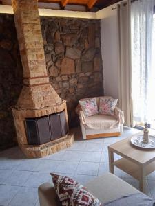 a living room with a stone wall with a fireplace at Traditional Stone House in Moudhros