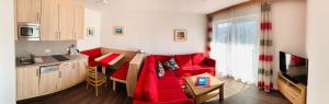 a living room with a red couch and a kitchen at Apartmenthaus Florian in Lam