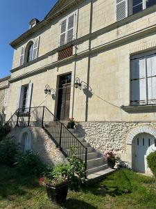 a stone building with a staircase leading to a door at Ancien relais de chasse à 35 min du Circuit 24h du Mans in Le Lude