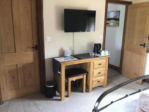 a room with a desk with a television on a wall at Owletts Barn B&B in Bodmin