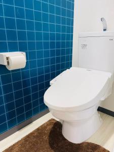 a white toilet in a blue tiled bathroom at 心斎橋、道頓堀徒歩10分！難波、黒門市場、徒歩圏内の最高の立地 in Osaka