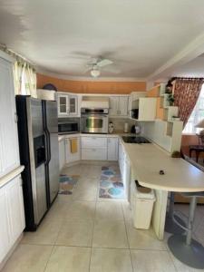 a kitchen with white cabinets and a black refrigerator at Cottage: 7 minutes from airport! in Saint Philip