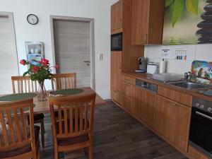 eine Küche mit Holzschränken sowie einem Tisch und Stühlen in der Unterkunft Ferienwohnung am Vareler Hafen/ Nordsee in Varel