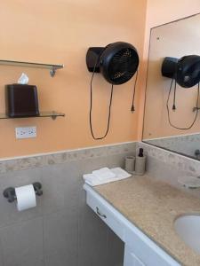 a bathroom with a sink and a fan on the wall at Cottage: 7 minutes from airport! in Saint Philip