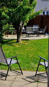 two chairs and a table in a park with a tree at 26 Woodgrove Drive in Inverness