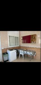 uma cozinha com uma mesa e um frigorífico branco em Chez Sarah em Beni Khiar