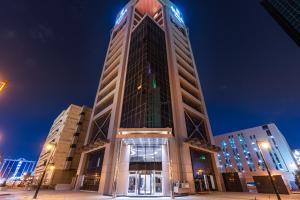 um edifício alto com uma torre de relógio à noite em Tura Hotel em Riyadh
