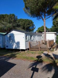 a white house with a fence and a tree at Mobile home camping Pedro in Le Grau-dʼAgde