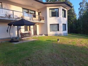 a dog standing in front of a house with an umbrella at Lakeside Villa Lehtiniemi in Pirkkala