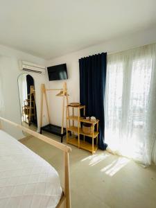 a bedroom with a bed and a window with blue curtains at Mykonian Starling - Town n' Sunset View Apartment in Mýkonos City