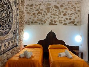 two twin beds in a room with orange sheets at Villaggio La Roccia camping in Lampedusa