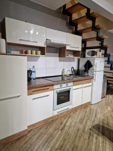uma cozinha com armários brancos e piso em madeira em Apartament PRZYBUDÓWKA em Katowice
