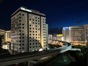 a tall white building in a city at night at Guest House Umikaji in Naha