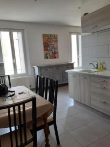 eine Küche mit einem Tisch, Stühlen und einem Waschbecken in der Unterkunft Maison de village - grand jardin in Saint-Quentin-la-Poterie