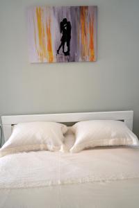a white bed with two pillows and a painting on the wall at Apartment Twins in Šibenik