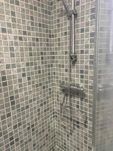 a shower in a bathroom with gray tiles at Chalet Urb Doña Violeta 500m Mar in Chiclana de la Frontera