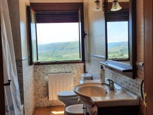a bathroom with a sink and a toilet and two windows at Casa rural Marcelina in Beteta
