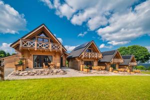 una casa de madera con un gran patio y césped en Domki Osada Zieleniec en Duszniki Zdrój