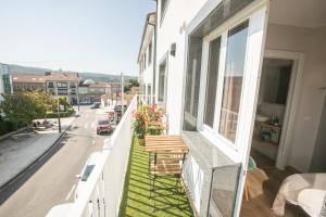 einen Balkon mit zwei Holzbänken auf einem Gebäude in der Unterkunft Pensión Lobre in O Pedrouzo