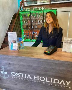 a woman standing behind a counter with a cell phone at Appartamento Gaudi in Lido di Ostia