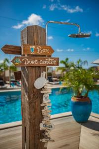 een houten bord met een bar/duikcentrum en een zwembad bij Bloozz resort Bonaire in Kralendijk