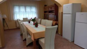 a dining room table with white chairs and a white refrigerator at Pension Casa Maria in Sovata