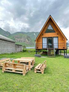 a cabin with benches and a table in the grass at Thomas' Hut in Kazbegi