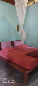 ein großes Bett mit einer roten Bettdecke und einem Vorhang in der Unterkunft Lawang Inn in Bukit Lawang