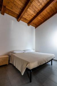 uma cama num quarto branco com tecto em madeira em La Conchiglia em Chioggia