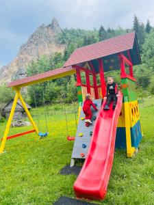two children are playing on a playground slide at Pensiunea Cheile Șugăului in Bicaz Chei