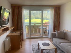 a living room with a couch and a large window at Kolbitsch am Weissensee ein Ausblick der verzaubert in Weissensee