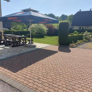 a picnic table with an umbrella on a brick patio at house Anna in Plitvička Jezera