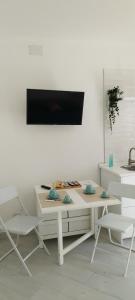 een witte tafel met twee stoelen en een tv aan de muur bij SoleMare Rooms "Smeraldo" in Procida