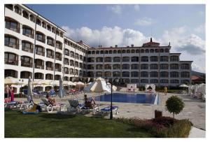 a large hotel with people sitting in chairs near a swimming pool at Aparthotel Regina Mare in Tsarevo