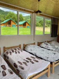 two beds in a room with windows and a house at Gusinje View in Gusinje